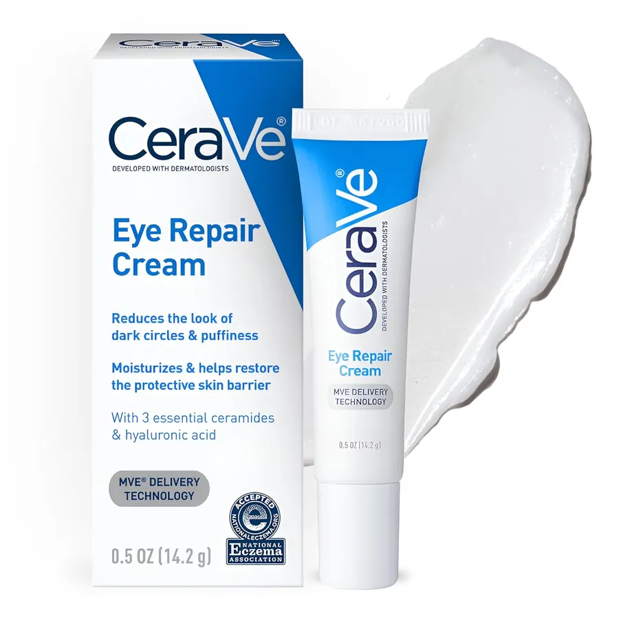 Close-up of a fingertip applying a small dot of white eye cream just below the outer corner of a closed eye